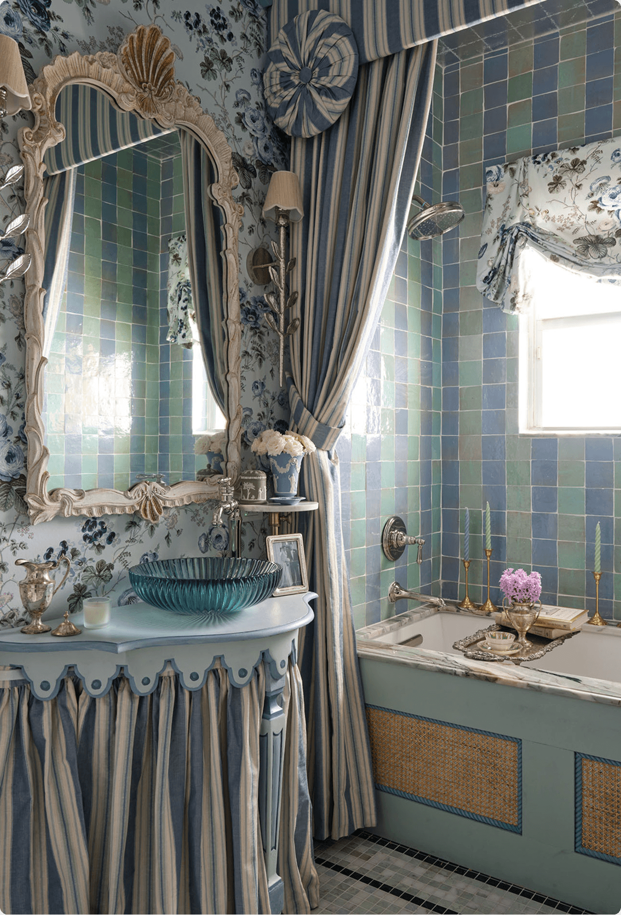 Ornate designer showhouse bathroom with blue-green tile, floral wallpaper, a shell-frame mirror, and Made Goods decor
